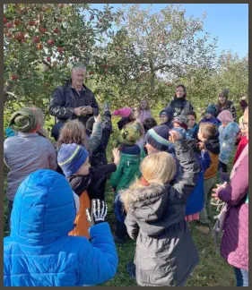 John Zekveld teaches the children how to pick apples on a tour